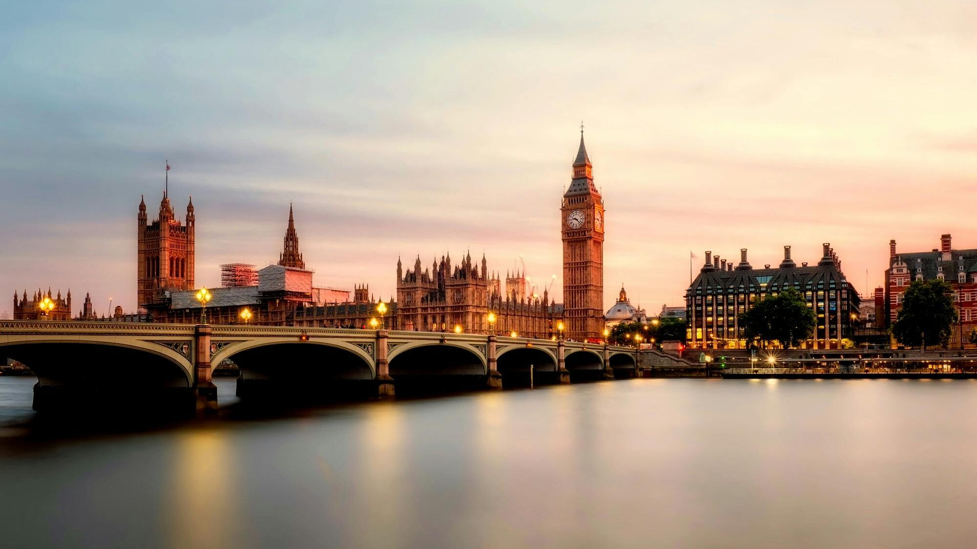 Scenic view of Big Ben and Westminster Bridge over the Thames River at sunset in London, UK.
